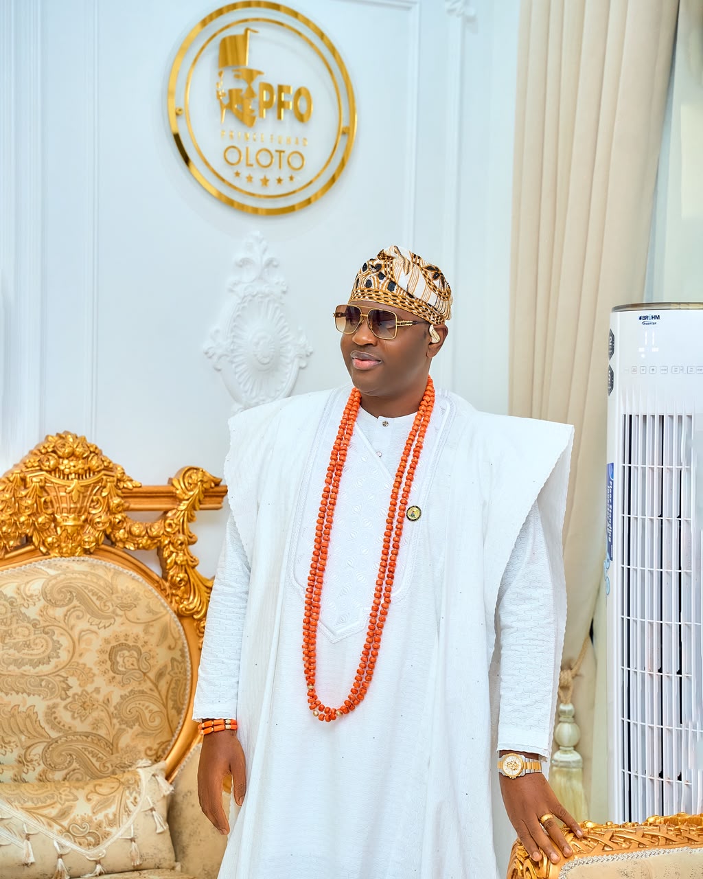 Prince Fuhad Oloto in royal attire beside the PFO crest