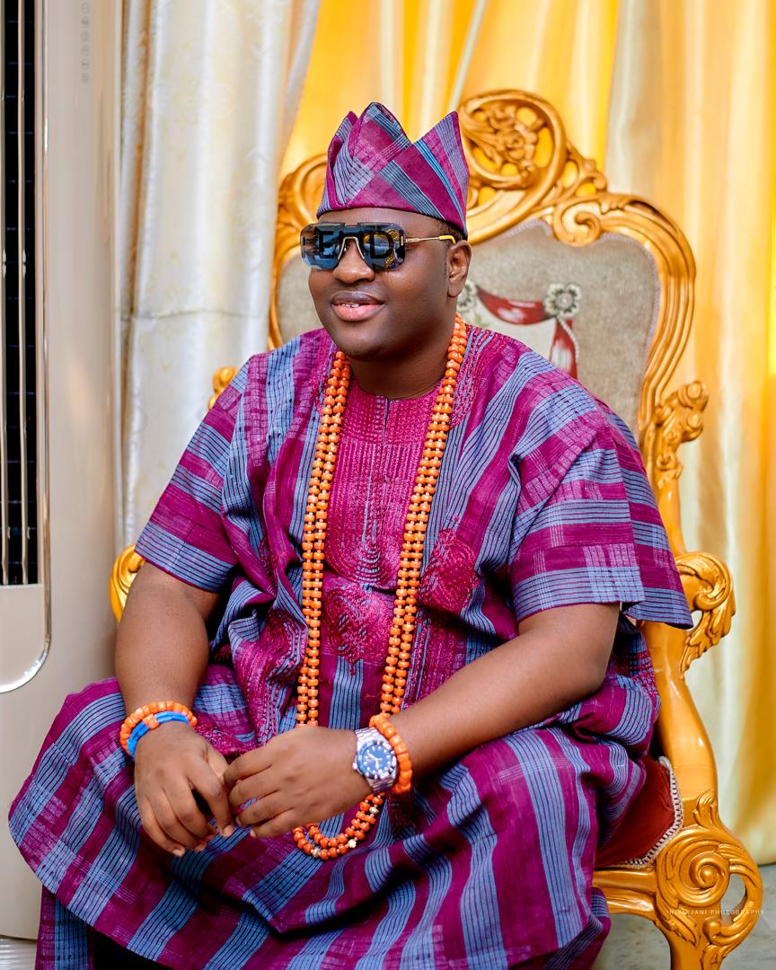 Prince Fuhad Oloto in magenta royal attire seated on the throne